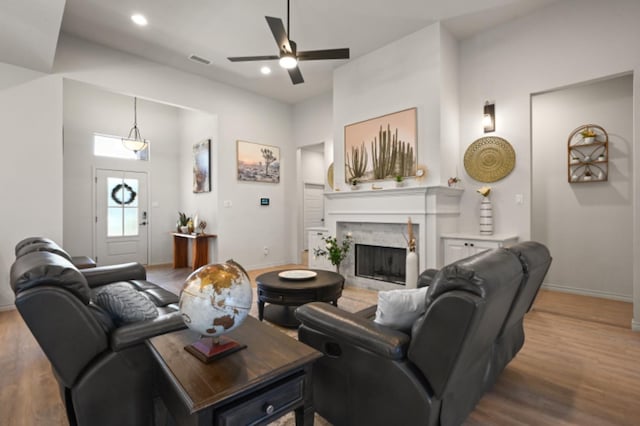 living room with hardwood / wood-style flooring, a high end fireplace, and ceiling fan