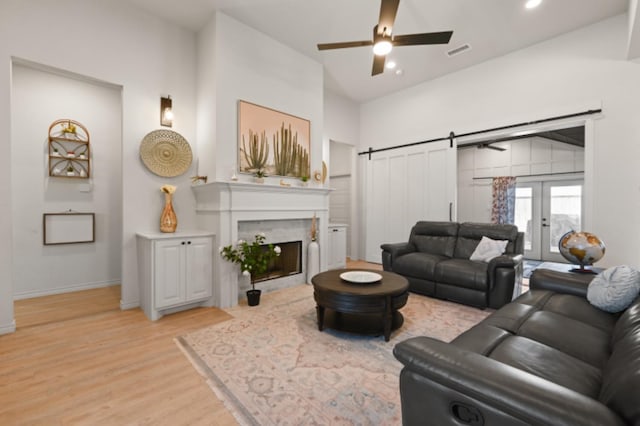 living room with a barn door, light hardwood / wood-style flooring, lofted ceiling, and french doors