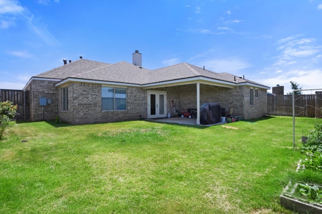 back of house with french doors, a patio area, and a lawn