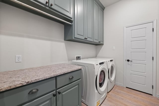 laundry room featuring cabinets, washer and clothes dryer, and light hardwood / wood-style flooring