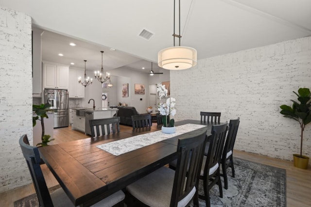 dining room with a chandelier, sink, and light wood-type flooring