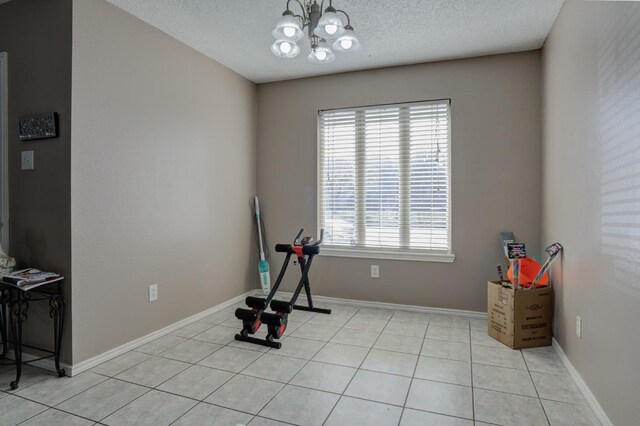 exercise room with light tile patterned flooring, an inviting chandelier, and a textured ceiling