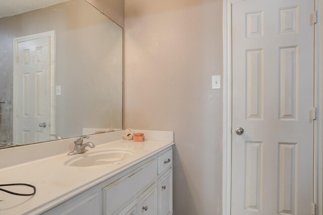 bedroom with ensuite bathroom, a textured ceiling, and light wood-type flooring