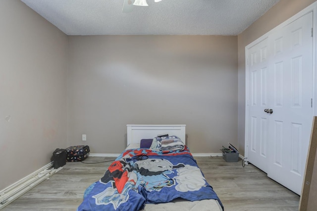 bedroom with ceiling fan, wood-type flooring, and a textured ceiling