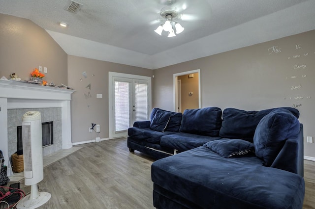 living room with a tile fireplace, vaulted ceiling, hardwood / wood-style floors, and ceiling fan