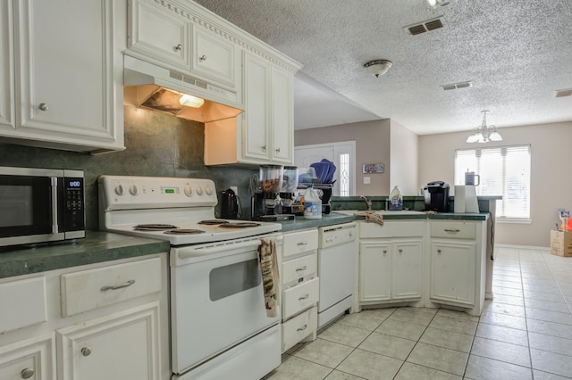 kitchen featuring white appliances, white cabinetry, an inviting chandelier, light tile patterned flooring, and kitchen peninsula