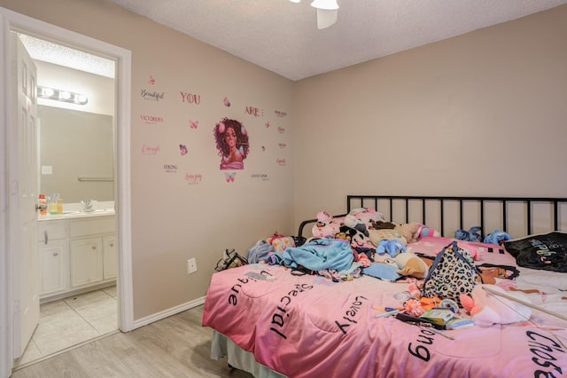 bedroom with ceiling fan, connected bathroom, a textured ceiling, and light hardwood / wood-style floors