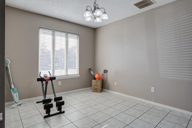 exercise area featuring light tile patterned floors, a notable chandelier, and a textured ceiling