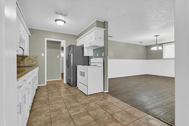 4802 54th St, Lubbock, TX 79414 - kitchen with white range, a textured ceiling, a chandelier, white cabinetry, and freestanding refrigerator