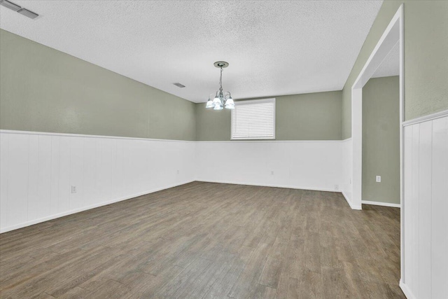 4802 54th St, Lubbock, TX 79414 - unfurnished room featuring wood finished floors, a textured ceiling, a wainscoted wall, and a chandelier