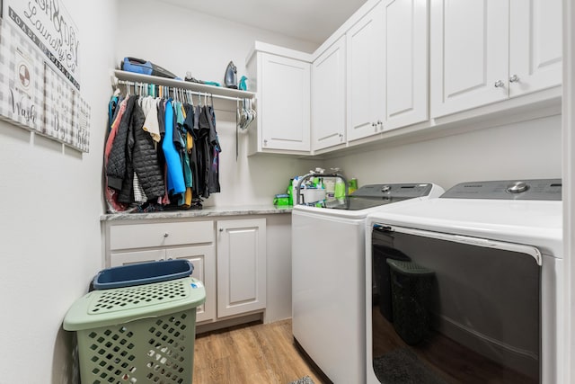 washroom with cabinet space, light wood-style flooring, and separate washer and dryer