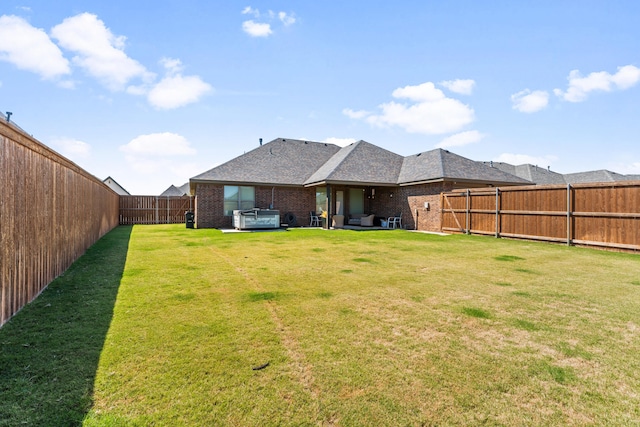 rear view of property featuring a yard, brick siding, and a fenced backyard