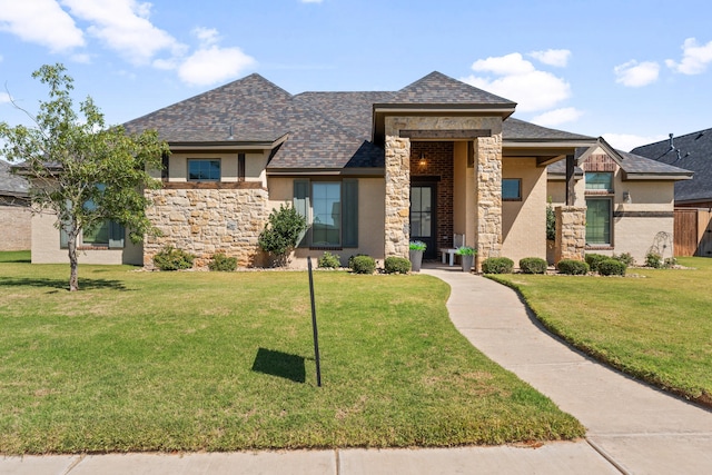 prairie-style home with stone siding, a front yard, and stucco siding