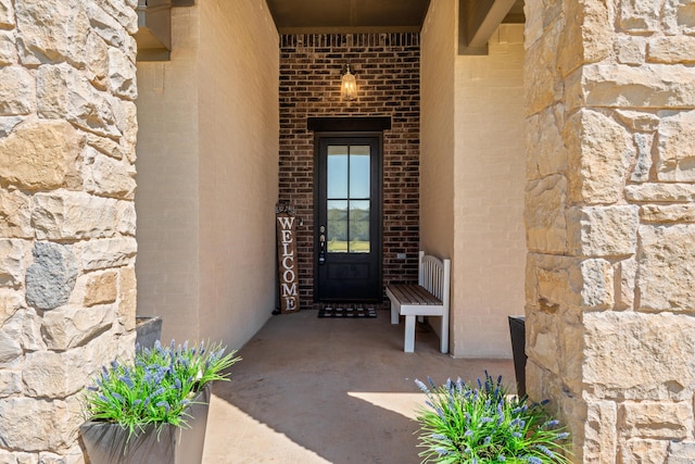 view of exterior entry featuring stucco siding and brick siding