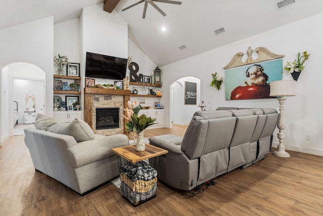 living room featuring arched walkways, visible vents, a fireplace, and wood finished floors