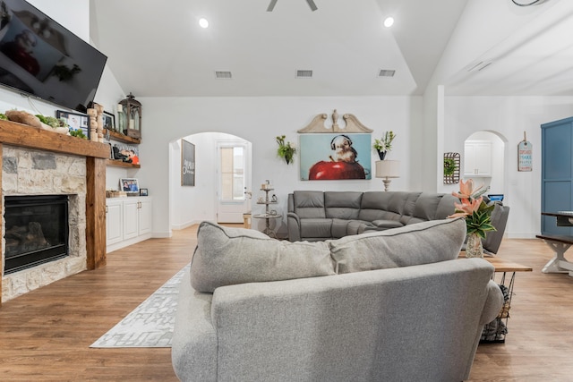 living area with visible vents, arched walkways, and a stone fireplace