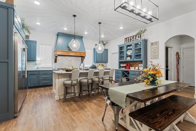 kitchen with hanging light fixtures, a kitchen island, glass insert cabinets, and light countertops