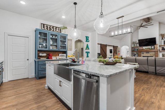 kitchen with arched walkways, a barn door, open floor plan, dishwasher, and glass insert cabinets