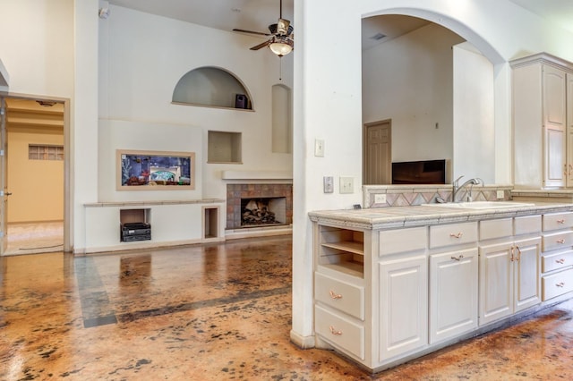 kitchen featuring white cabinetry, sink, a towering ceiling, and ceiling fan