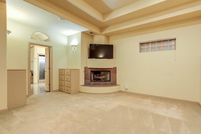 unfurnished living room with a raised ceiling, a tile fireplace, and carpet