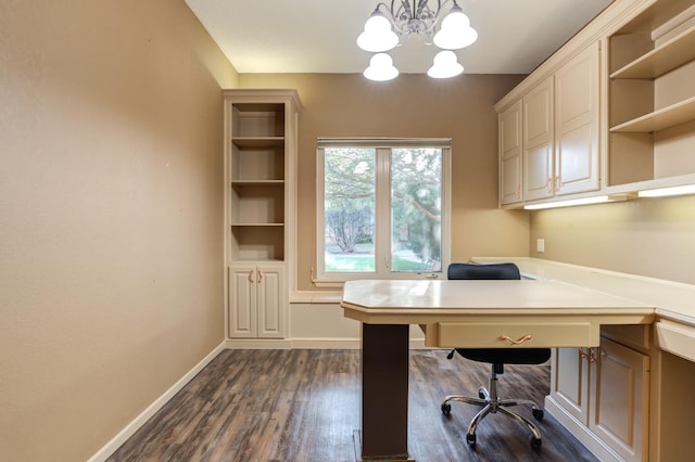 unfurnished office with dark wood-type flooring, built in desk, and a notable chandelier