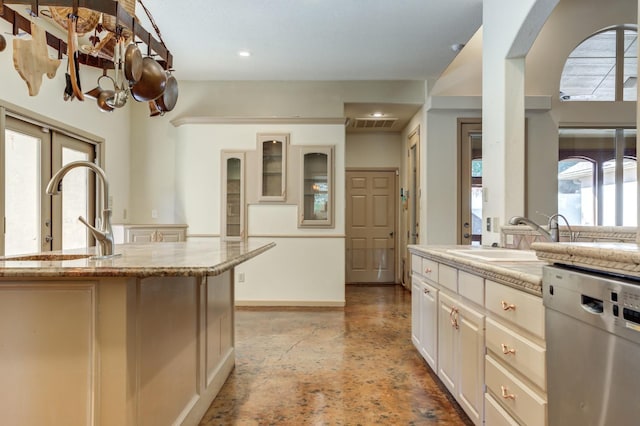 kitchen featuring light stone counters, dishwasher, and sink