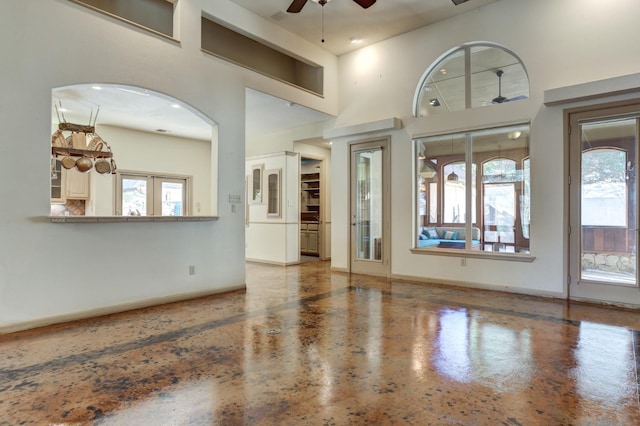 unfurnished living room featuring a high ceiling and ceiling fan