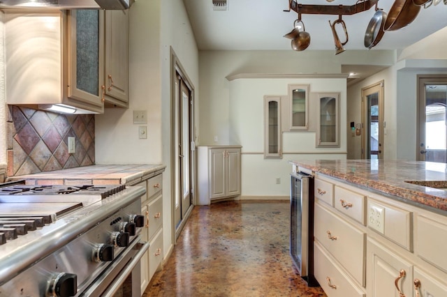 kitchen featuring cream cabinets, high end stove, and beverage cooler