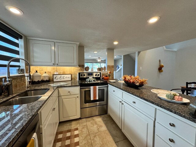 kitchen with sink, stainless steel range with electric cooktop, white cabinetry, tasteful backsplash, and dark stone countertops