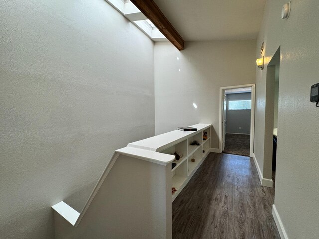 corridor featuring beamed ceiling, dark hardwood / wood-style floors, and a skylight