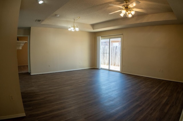 empty room with dark hardwood / wood-style flooring, ceiling fan with notable chandelier, and a raised ceiling