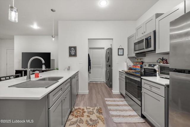 1203 N Evanston Ave, Lubbock, TX 79416 - kitchen featuring stainless steel appliances, estacked washer and dryer, gray cabinets, a peninsula, and light wood finished floors