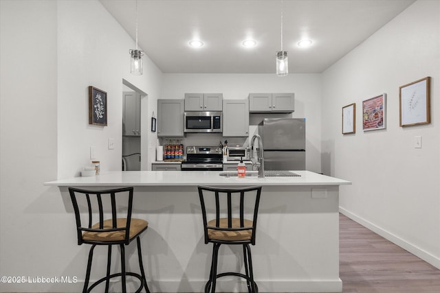 1203 N Evanston Ave, Lubbock, TX 79416 - kitchen featuring appliances with stainless steel finishes, gray cabinetry, light countertops, a kitchen breakfast bar, and recessed lighting