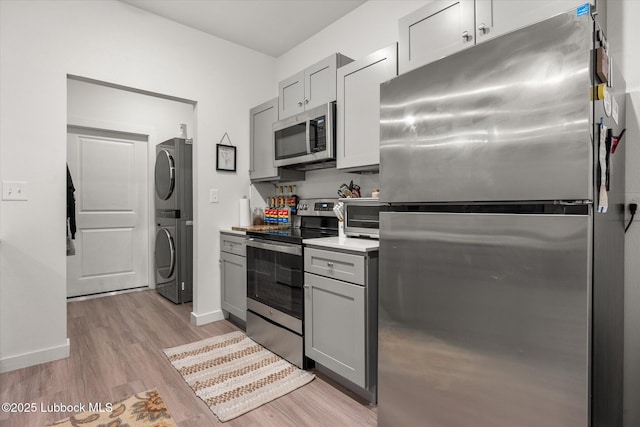 1203 N Evanston Ave, Lubbock, TX 79416 - kitchen featuring stainless steel appliances, stacked washer / drying machine, gray cabinets, light wood-style floors, and light countertops