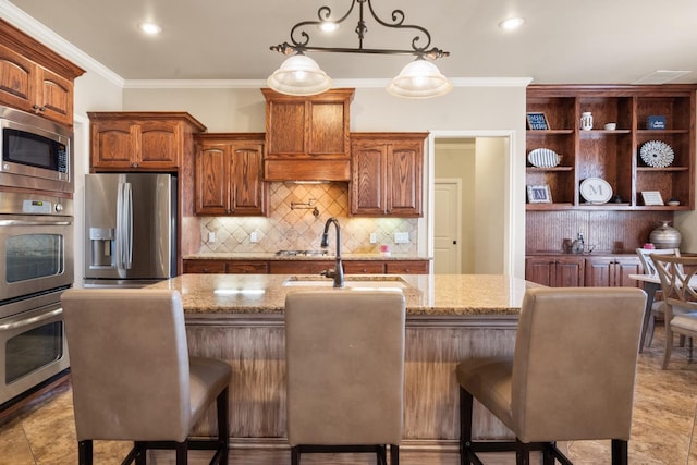 kitchen with a sink, stainless steel appliances, light stone counters, and ornamental molding