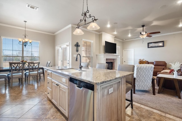 kitchen featuring visible vents, a center island with sink, a sink, stainless steel dishwasher, and a fireplace