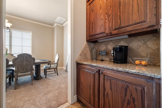 kitchen featuring light stone counters, baseboards, ornamental molding, decorative backsplash, and light carpet