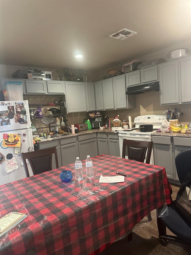 kitchen with white appliances, light stone countertops, and gray cabinetry