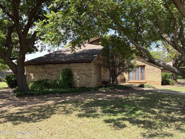 1423 Cherry Blossom Dr, Littlefield, TX 79339 - view of side of home with brick siding and a yard