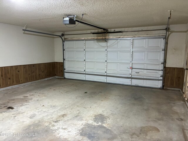 1423 Cherry Blossom Dr, Littlefield, TX 79339 - garage with wood walls, a garage door opener, and wainscoting