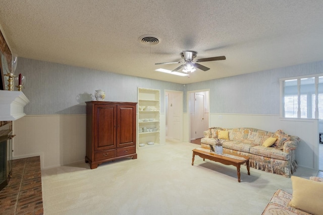 carpeted living room featuring ceiling fan, a fireplace, and a textured ceiling