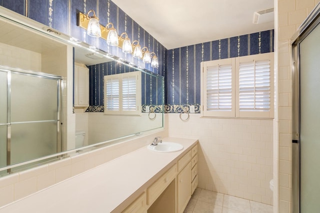 bathroom with tile patterned flooring, an enclosed shower, vanity, and tile walls