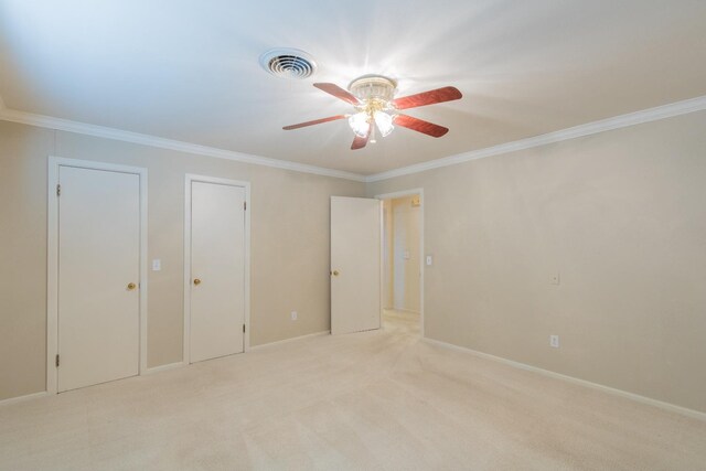 unfurnished bedroom with ceiling fan, ornamental molding, light carpet, and two closets