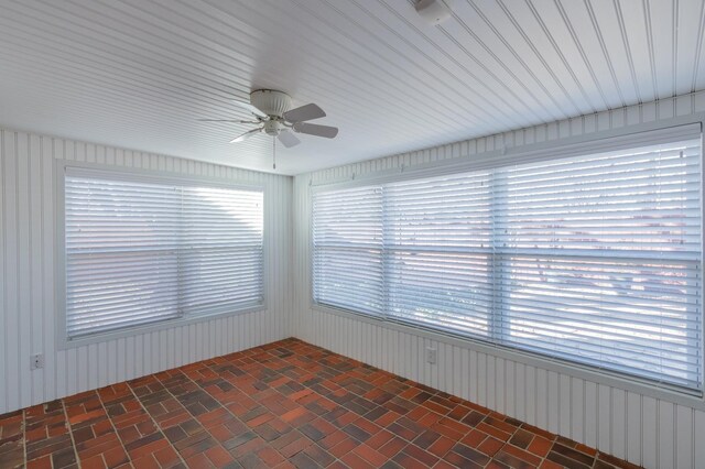 unfurnished sunroom featuring ceiling fan