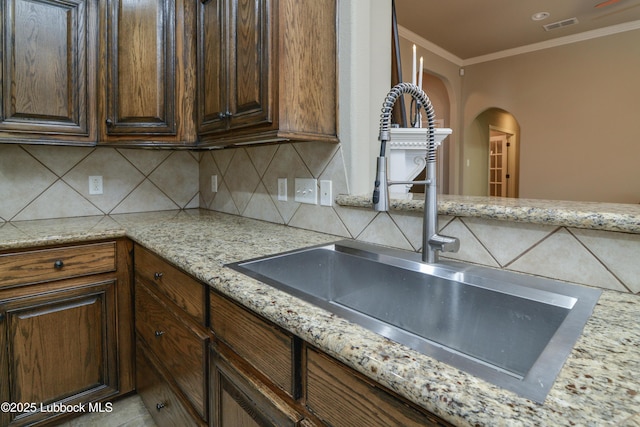 5901 102nd St, Lubbock, TX 79424 - kitchen with a sink, arched walkways, backsplash, ornamental molding, and light stone countertops