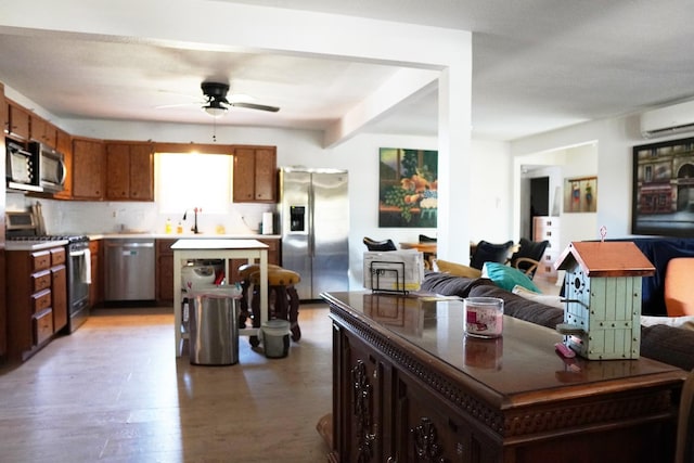 kitchen with a wall unit AC, a kitchen island, hardwood / wood-style flooring, ceiling fan, and stainless steel appliances