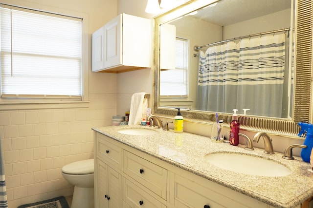 bathroom featuring tile walls, vanity, toilet, and a healthy amount of sunlight