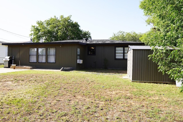 back of house featuring a storage shed and a yard