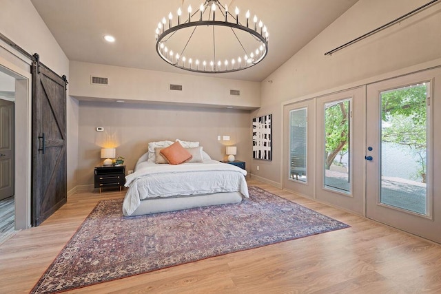 bedroom featuring light wood-type flooring, access to exterior, visible vents, and a barn door