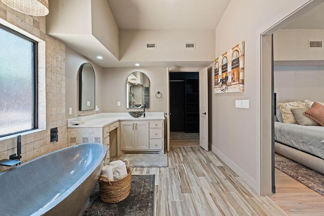 bathroom featuring visible vents, a soaking tub, wood finished floors, and vanity